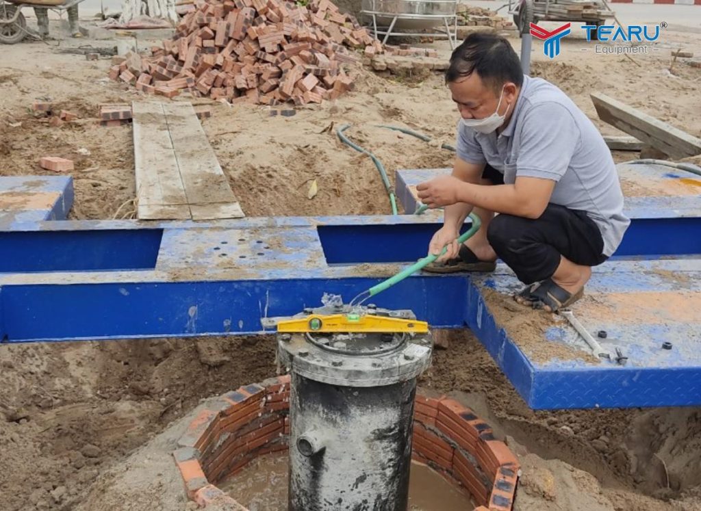 Hướng Dẫn Kỹ Thuật Đào Hố Móng Cầu Nâng 1 Trụ Chi Tiết Từ A–Z 3 Khi đặt trụ cầu nâng vào hố móng Dùng thước nivo cân chỉnh trụ thẳng tuyệt đối